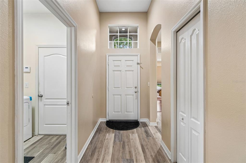An entryway features a white front door, light-colored walls, and wood-look vinyl plank flooring — 211 FAIRMONT DRIVE, SPRING HILL, FL