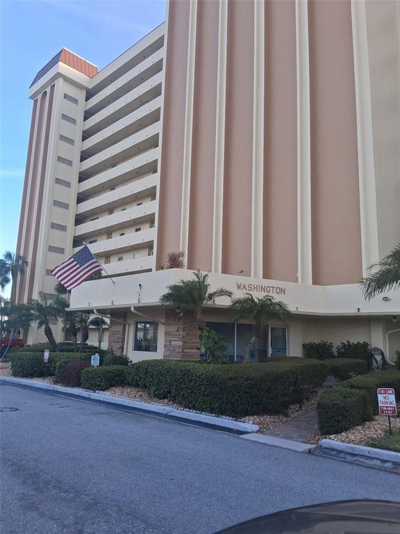 A multi-story beige apartment building with a prominent American flag and a "Washington" sign — 4550 COVE CIRCLE UNIT 505, ST PETERSBURG, FL