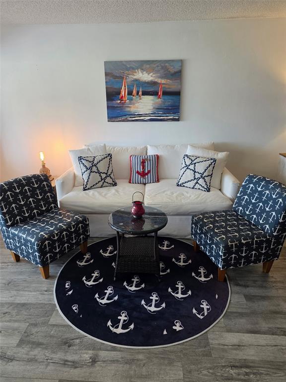 A living room features a white sofa, two anchor-patterned armchairs, and a round anchor rug — 4550 COVE CIRCLE UNIT 505, ST PETERSBURG, FL