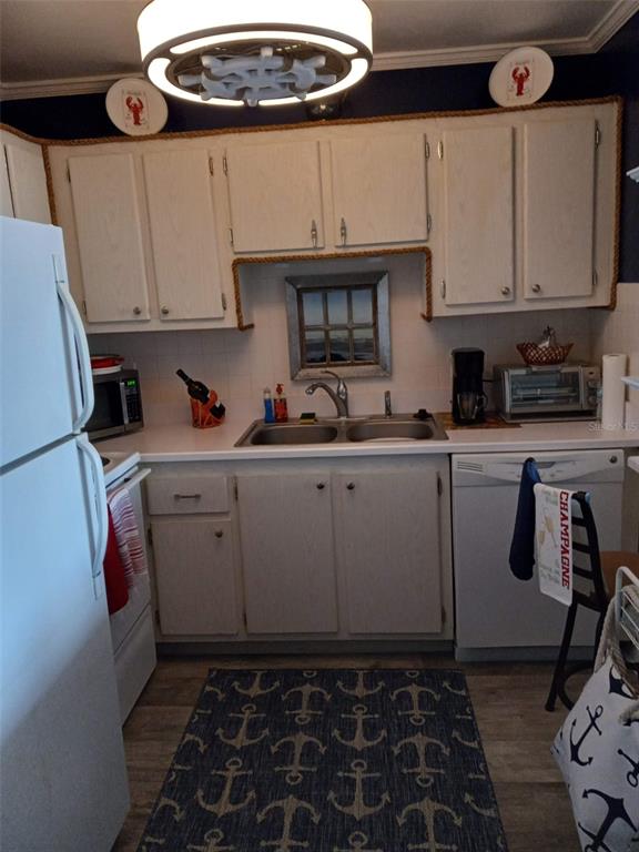 A kitchen features white cabinets, a double sink, nautical-themed decor, and an anchor-patterned rug — 4550 COVE CIRCLE UNIT 505, ST PETERSBURG, FL