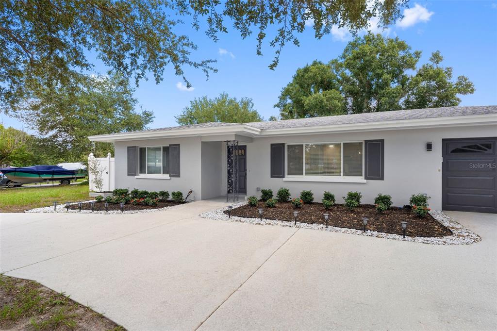 A single-story house with a gray exterior, dark shutters, and a concrete driveway — 1601 HARDWOOD DRIVE, CLEARWATER, FL