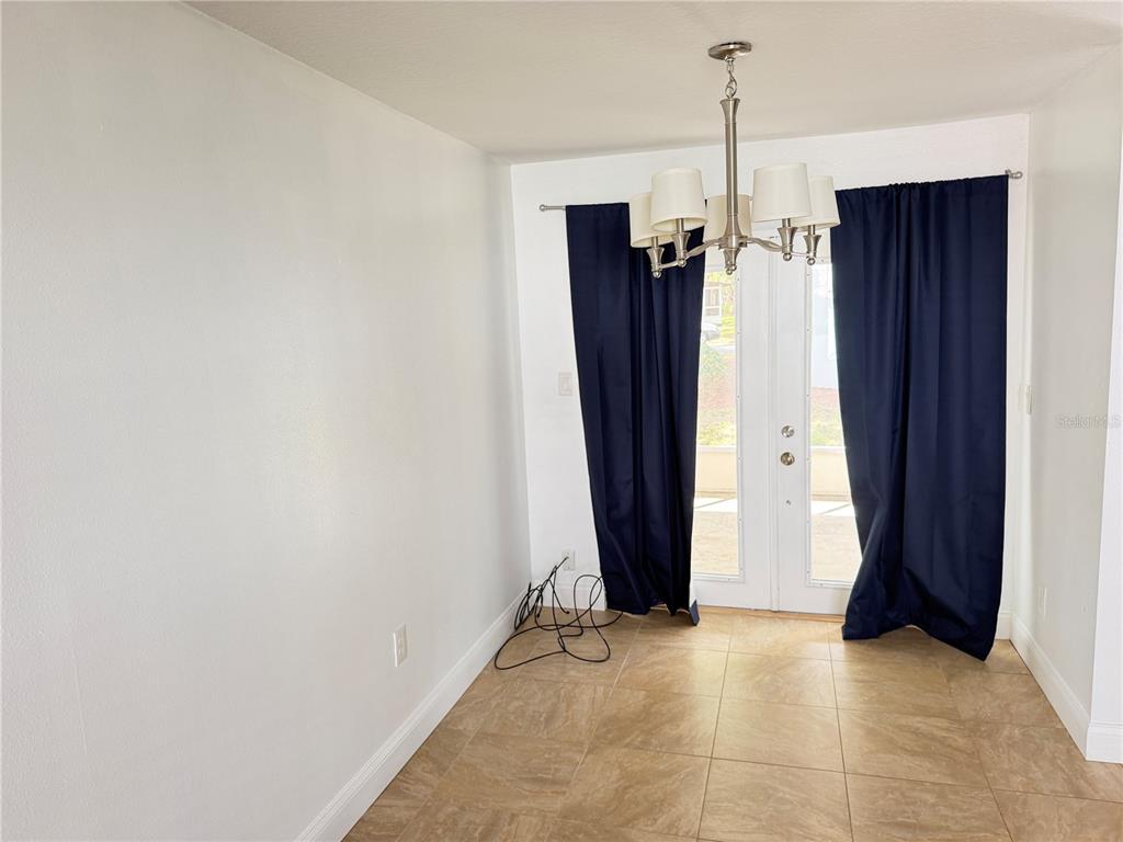 A dining area features tile flooring, a chandelier, and dark curtains over glass doors — 2564 SE 15TH AVENUE UNIT H, OCALA, FL