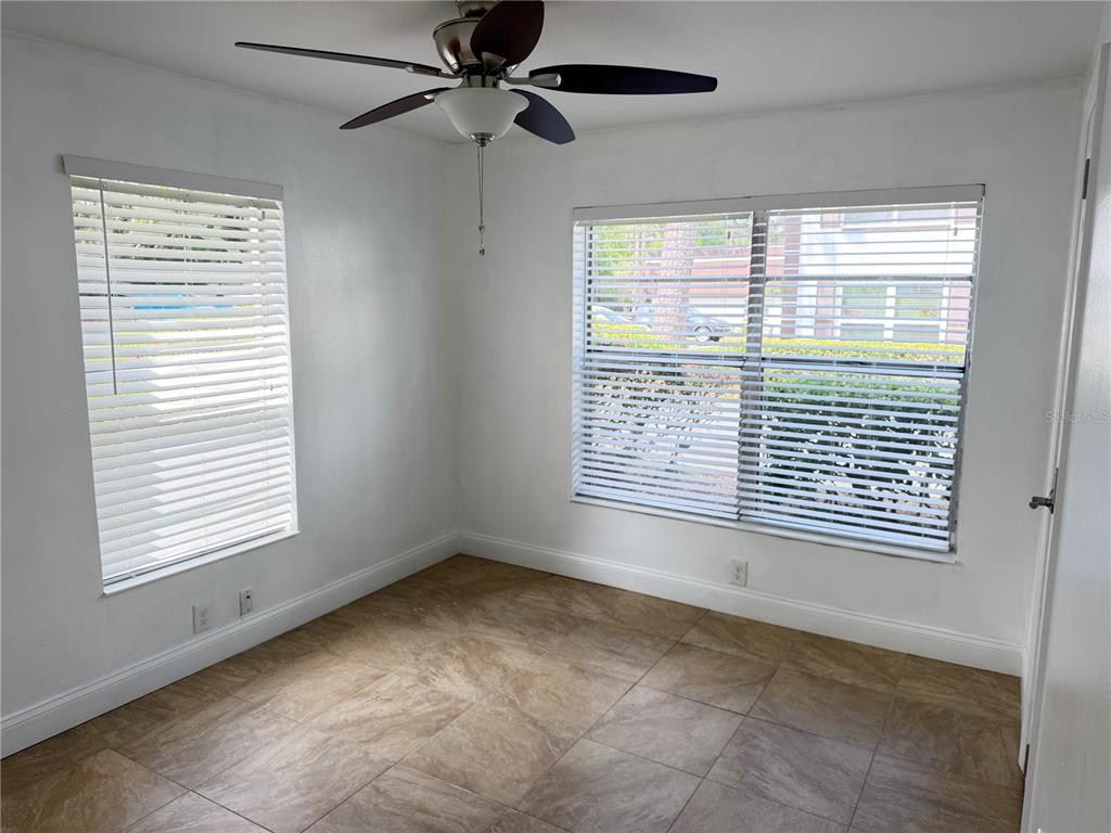 An empty room features white walls, tile flooring, a ceiling fan, and two windows with blinds — 2564 SE 15TH AVENUE UNIT H, OCALA, FL