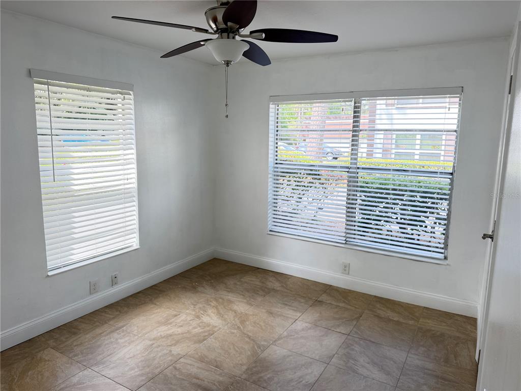 An empty room with white walls, tile flooring, a ceiling fan, and two shuttered windows — 2564 SE 15TH AVENUE UNIT H, OCALA, FL