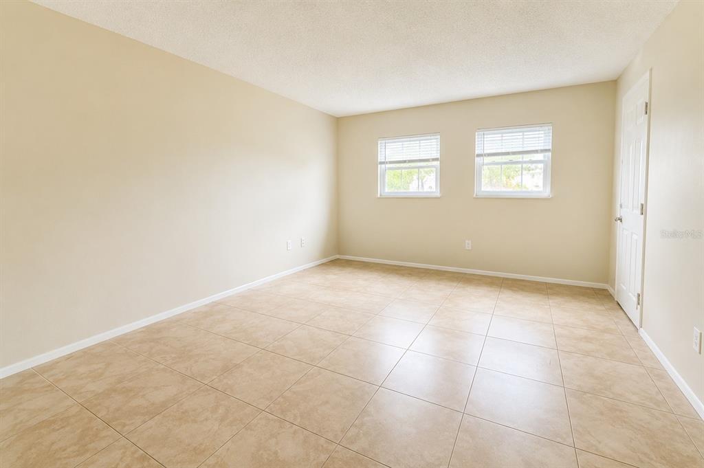 An empty room features beige walls, light-colored tile flooring, and two windows with white blinds — 828 SKY LAKE CIRCLE UNIT B, ORLANDO, FL