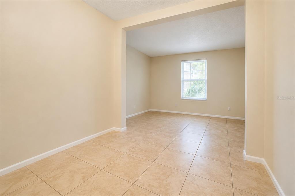 An empty room with beige walls and light-colored tile flooring features a single window — 828 SKY LAKE CIRCLE UNIT B, ORLANDO, FL