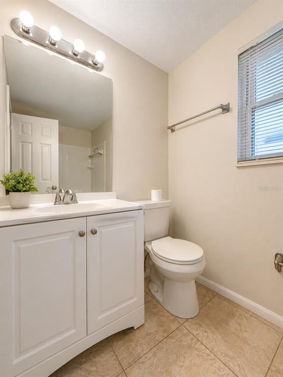 A bathroom with a white vanity, a toilet, a mirror, and a window with blinds — 828 SKY LAKE CIRCLE UNIT B, ORLANDO, FL
