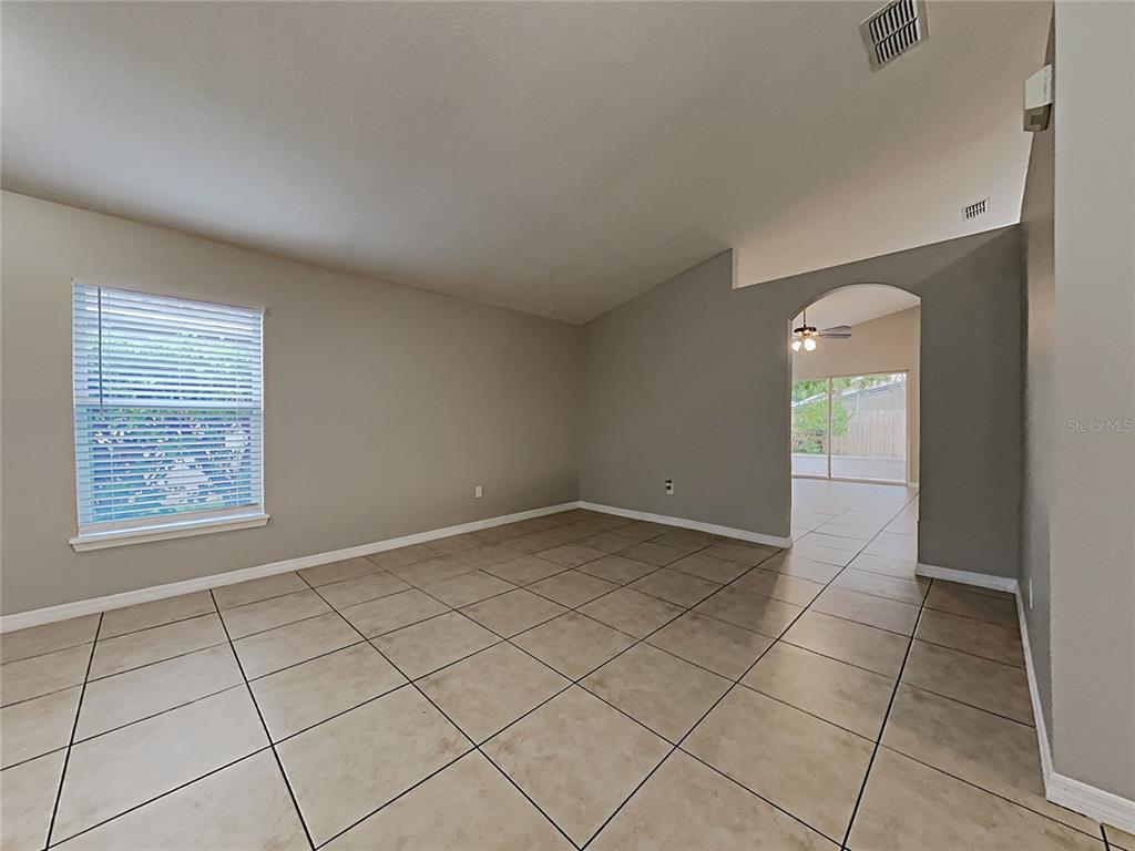 An empty room with beige tile flooring, light gray walls, and an arched entryway — 511 WELLESLY STREET, OVIEDO, FL