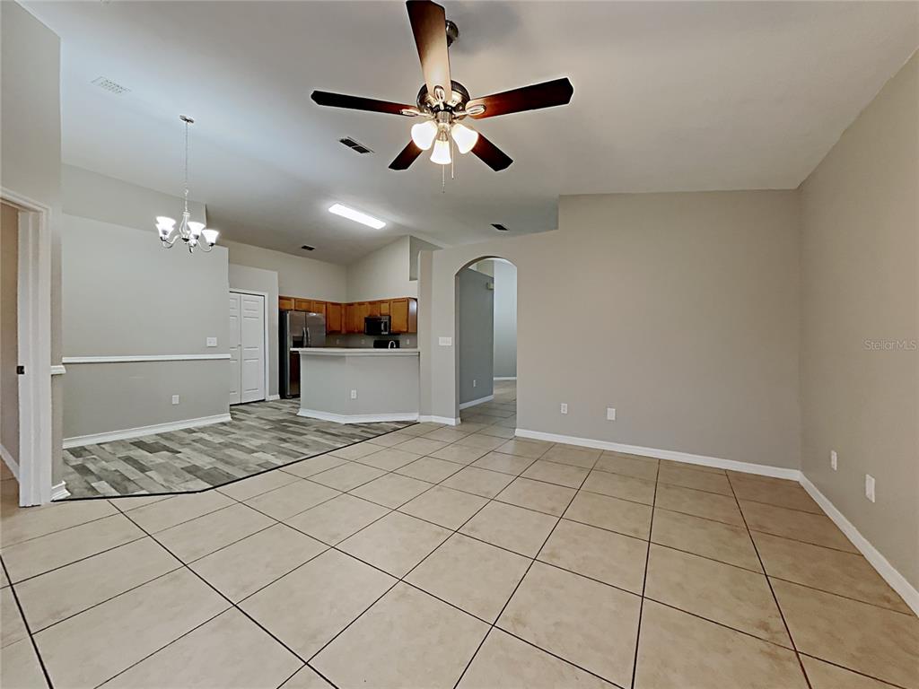 An open-concept living area features tile flooring, a ceiling fan, and an adjacent kitchen — 511 WELLESLY STREET, OVIEDO, FL