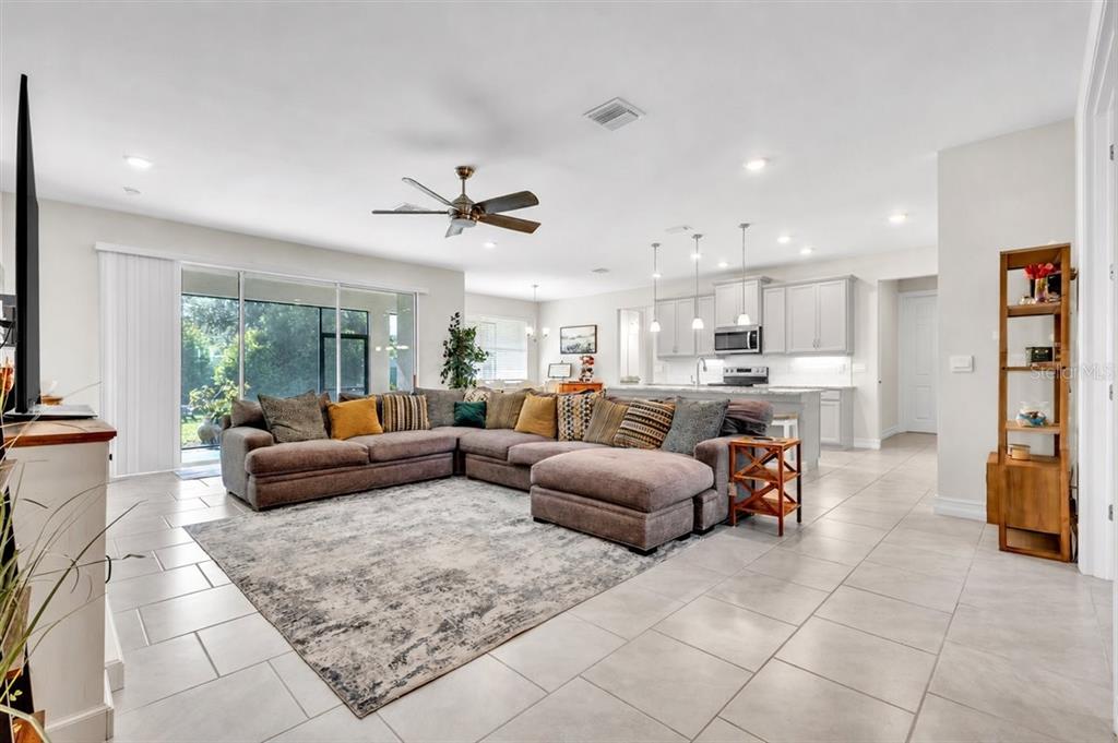 An open-concept living room features a large sectional sofa, tile flooring, and a kitchen island — 2065 NUREMBERG BOULEVARD, PUNTA GORDA, FL