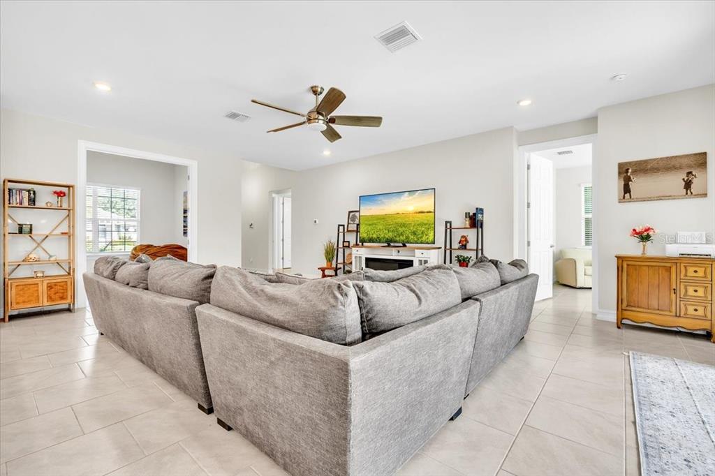 A spacious living room features a large gray sectional sofa, a ceiling fan, and tile flooring — 2065 NUREMBERG BOULEVARD, PUNTA GORDA, FL
