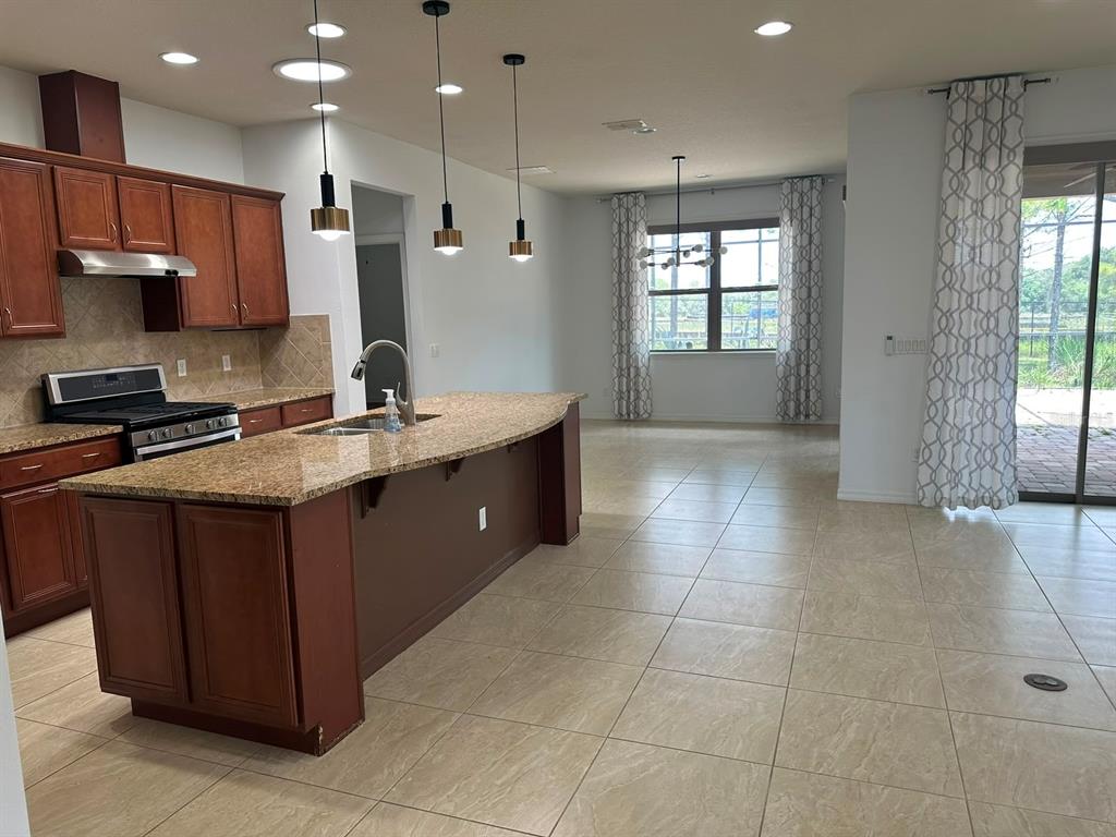 A kitchen with wood cabinets and a granite island opens into a dining area — 333 NAVARRA LANE, DAVENPORT, FL