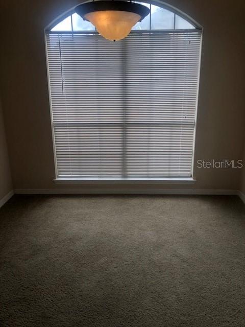 A carpeted room features a large arched window covered by horizontal blinds and a pendant light — 10961 BURNT MILL ROAD UNIT 1518, JACKSONVILLE, FL