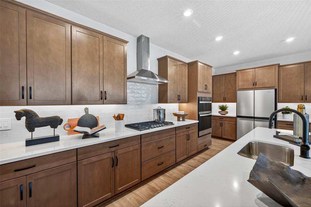 A modern kitchen features wood cabinets, white countertops, stainless steel appliances, and a center island — 34890 FLOWER PATCH DRIVE, DADE CITY, FL