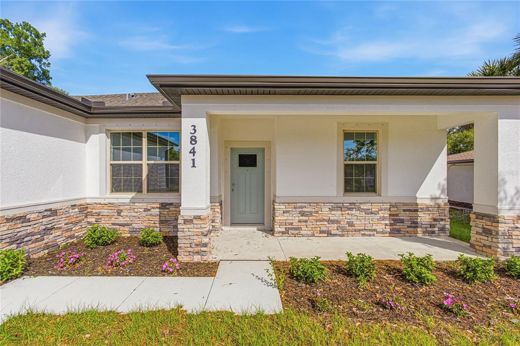 The exterior of a house features a light blue front door, stone veneer, and landscaping — 4446 LARATONDA ROAD, NORTH PORT, FL