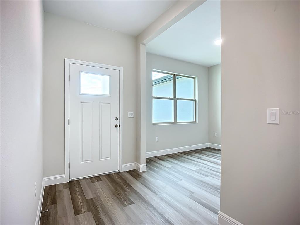 An entryway with a white door and wood-look flooring leads into a bright room — 4446 LARATONDA ROAD, NORTH PORT, FL