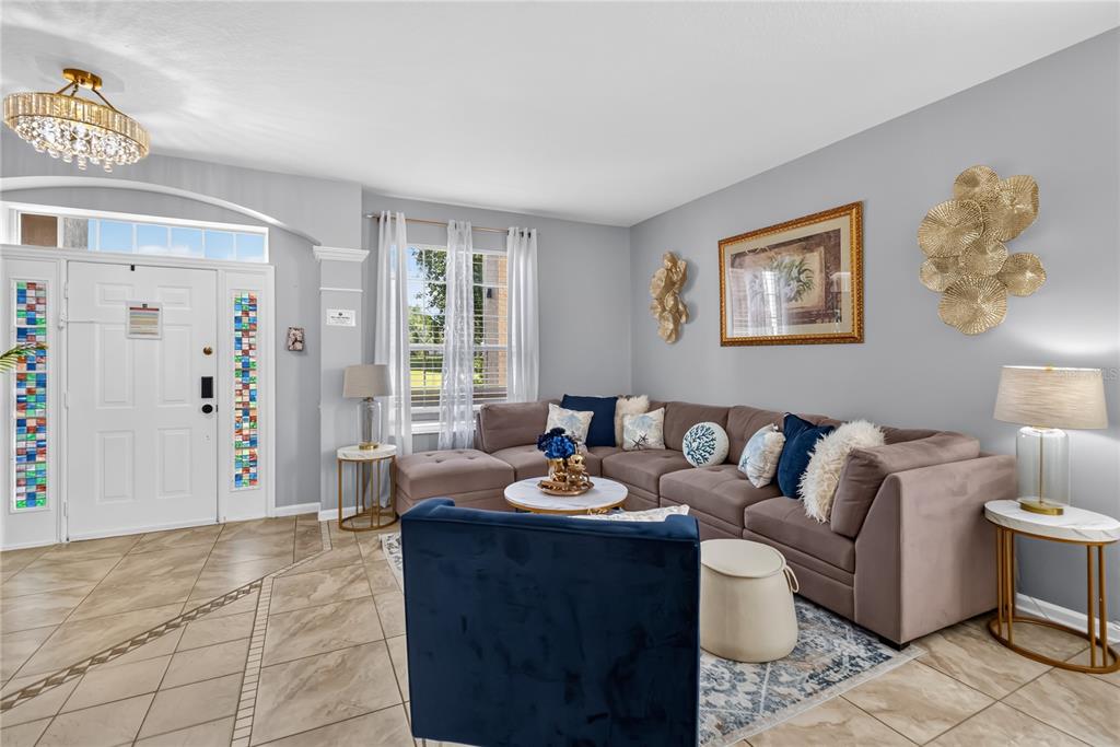A living room features a large brown sectional, a blue armchair, and tile flooring — 8006 KING PALM CIRCLE, KISSIMMEE, FL