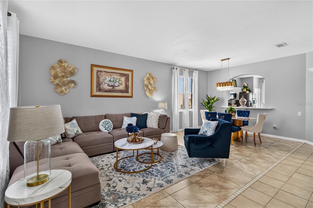A living room and dining area with gray walls, tile floors, and blue accent furniture — 8006 KING PALM CIRCLE, KISSIMMEE, FL