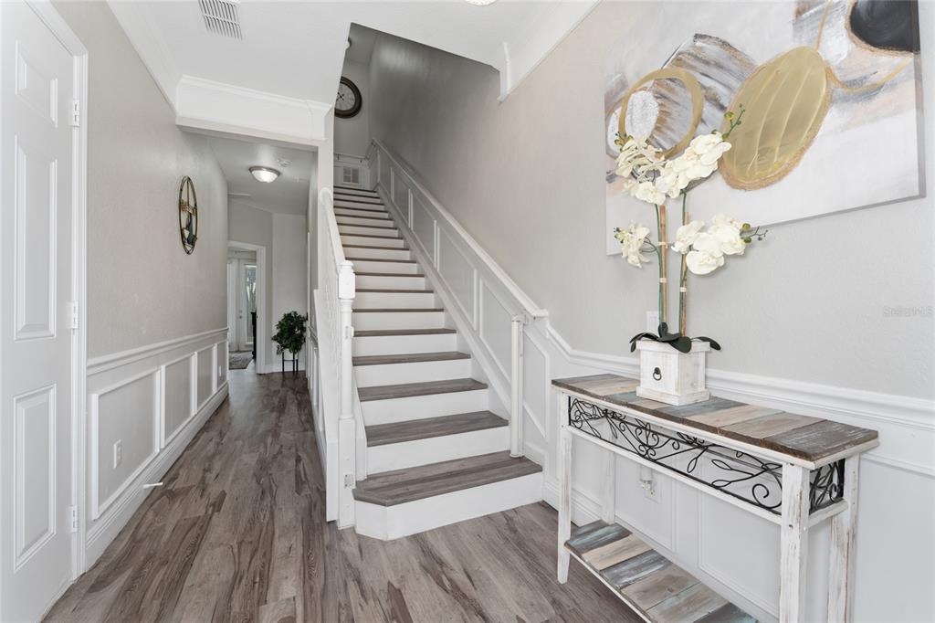 A foyer features a staircase with wood-look treads, white wainscoting, and a console table — 5026 TIDEVIEW CIRCLE UNIT 17, ORLANDO, FL