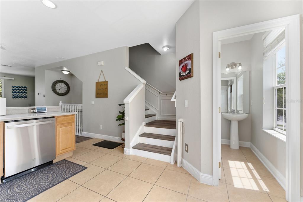 A kitchen with stainless steel appliances, a staircase, and an adjacent half bathroom — 5026 TIDEVIEW CIRCLE UNIT 17, ORLANDO, FL