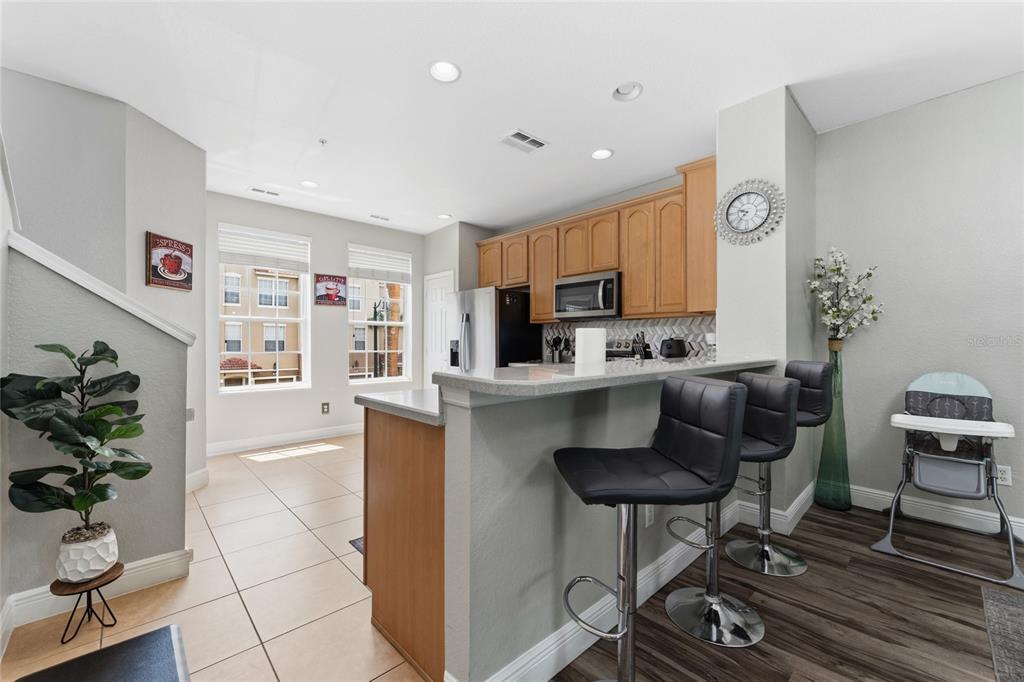A kitchen features light wood cabinets, a breakfast bar with stools, and tile flooring — 5026 TIDEVIEW CIRCLE UNIT 17, ORLANDO, FL