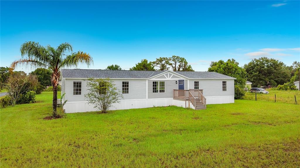 A single-story manufactured home with light gray siding and a small wooden front porch — 9200 MERCURY DRIVE, ST CLOUD, FL