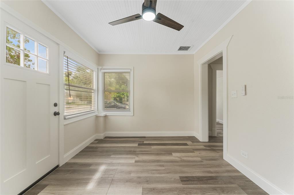 A sunroom features light wood-look flooring, white walls, a ceiling fan, and multiple windows — 1922 23RD STREET S, ST PETERSBURG, FL