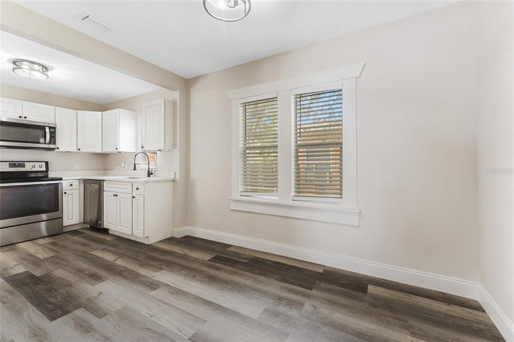 An empty room features wood-look flooring, a ceiling fan, and windows with white blinds — 1922 23RD STREET S, ST PETERSBURG, FL