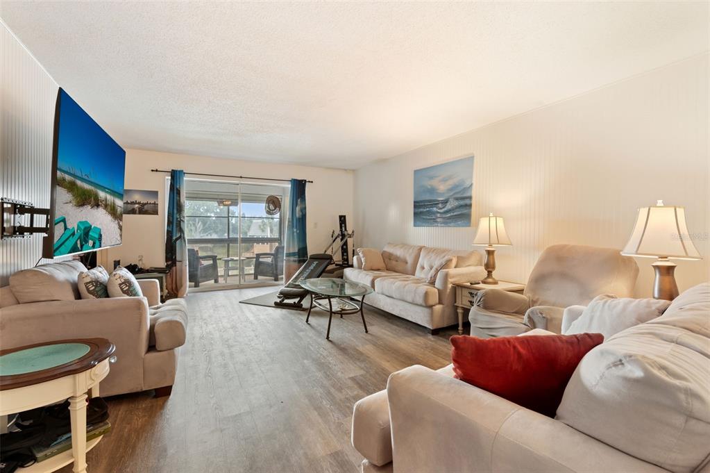 A living room features light-colored sofas, a glass coffee table, wood-look flooring, and a television — 719 CORDOVA GREEN UNIT 719, SEMINOLE, FL