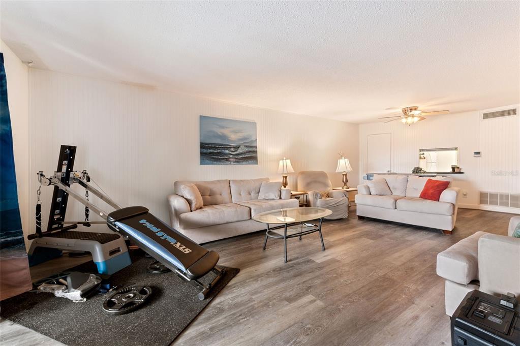 A living room features light-colored sofas, a Total Gym exercise machine, and wood-look flooring — 719 CORDOVA GREEN UNIT 719, SEMINOLE, FL
