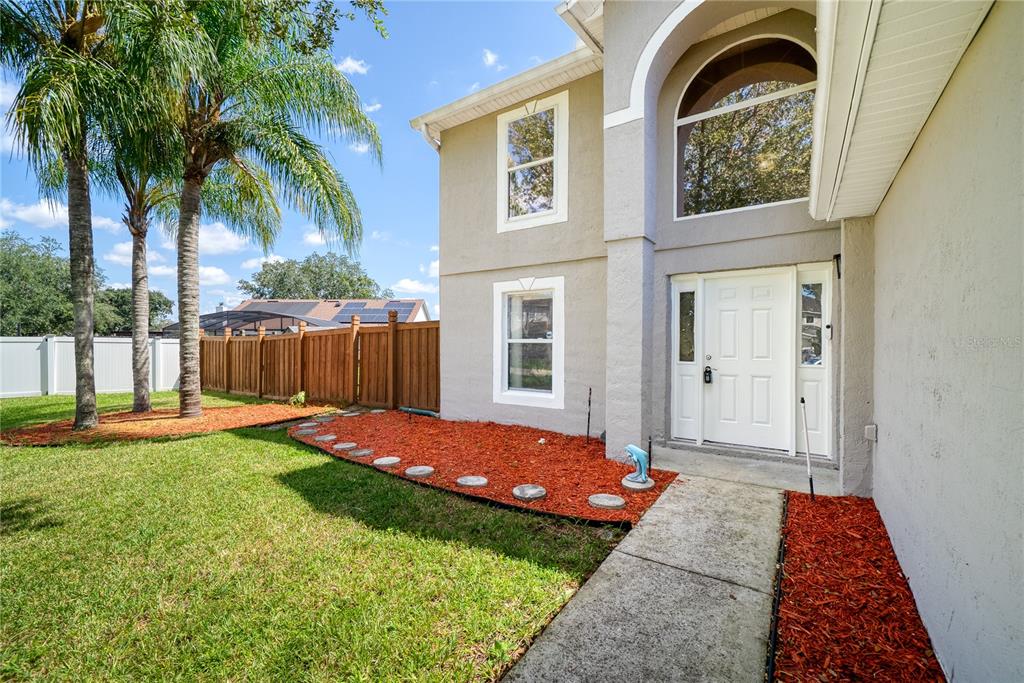 A two-story house exterior features a white front door, red mulch beds, and palm trees — 3209 ROMAINE COURT, ORLANDO, FL