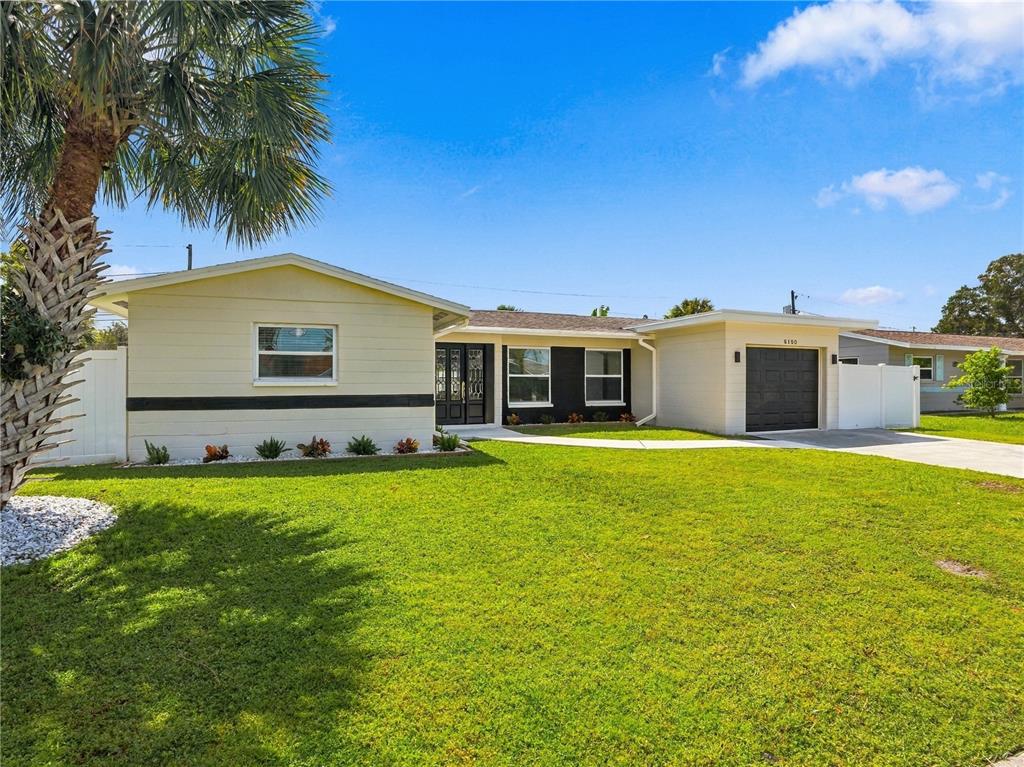 A single-story house with a light-colored exterior, a black garage door, and a palm tree — 6150 31ST AVENUE N, ST PETERSBURG, FL