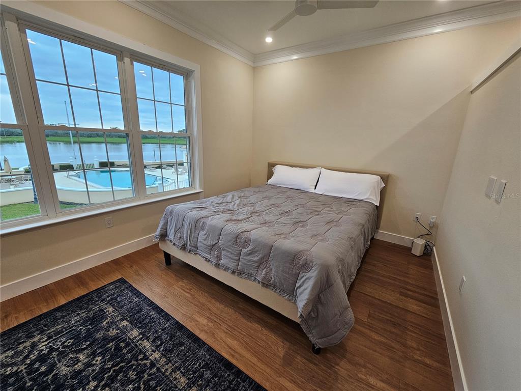 A bedroom with wood flooring, a bed, and large windows overlooking a swimming pool — 51 MAC EWEN DRIVE UNIT 14, OSPREY, FL
