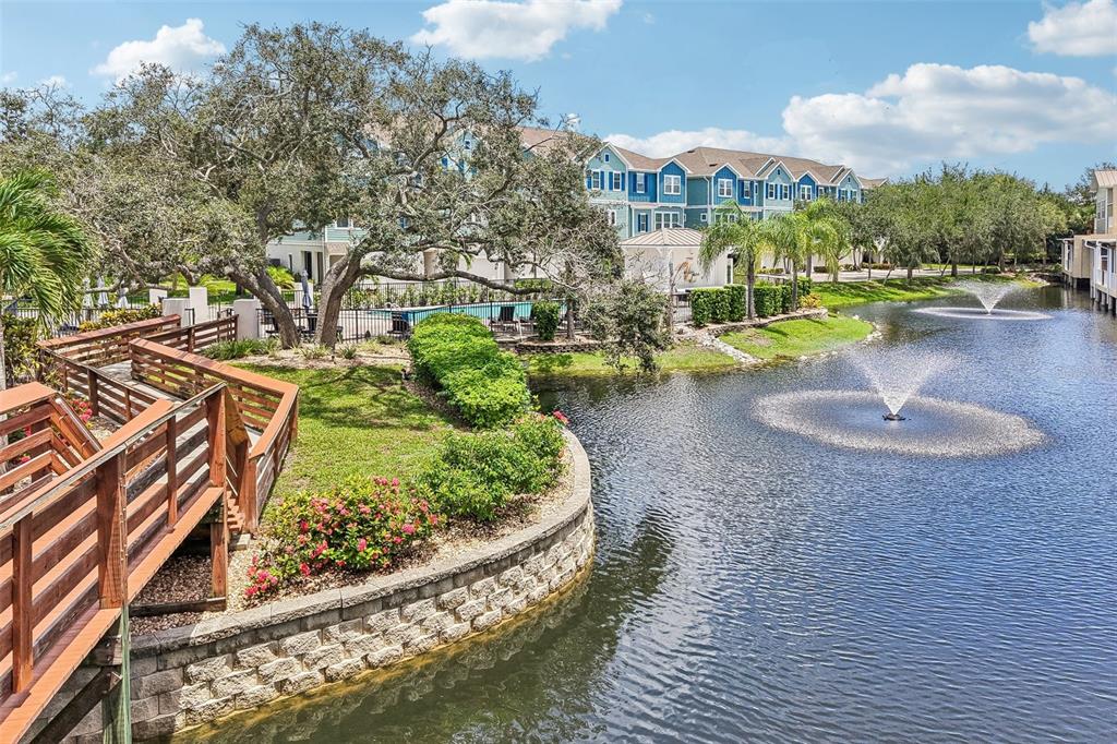 The exterior of a multi-unit townhouse complex features three brown garage doors and a tree — 131 ATHENIAN WAY, TARPON SPRINGS, FL