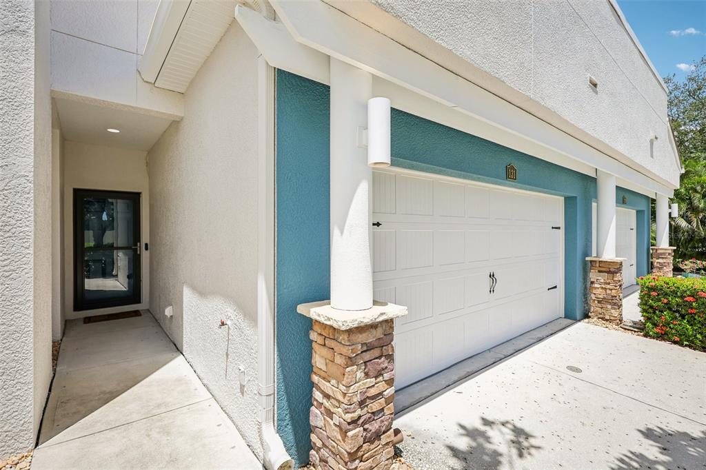 An open-concept living and dining area features light wood flooring, a metal railing, and artwork — 131 ATHENIAN WAY, TARPON SPRINGS, FL