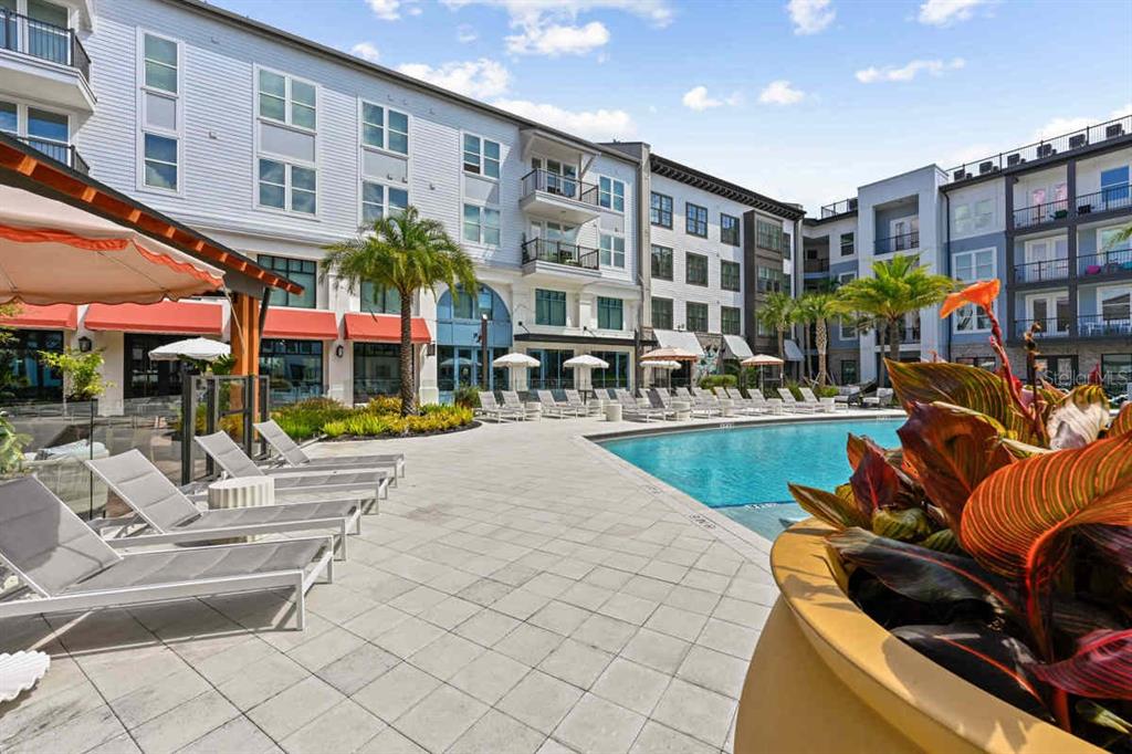 A swimming pool area with lounge chairs and a large planter in the foreground — 1464 LAUREL SOUND LANE UNIT C1, SANFORD, FL