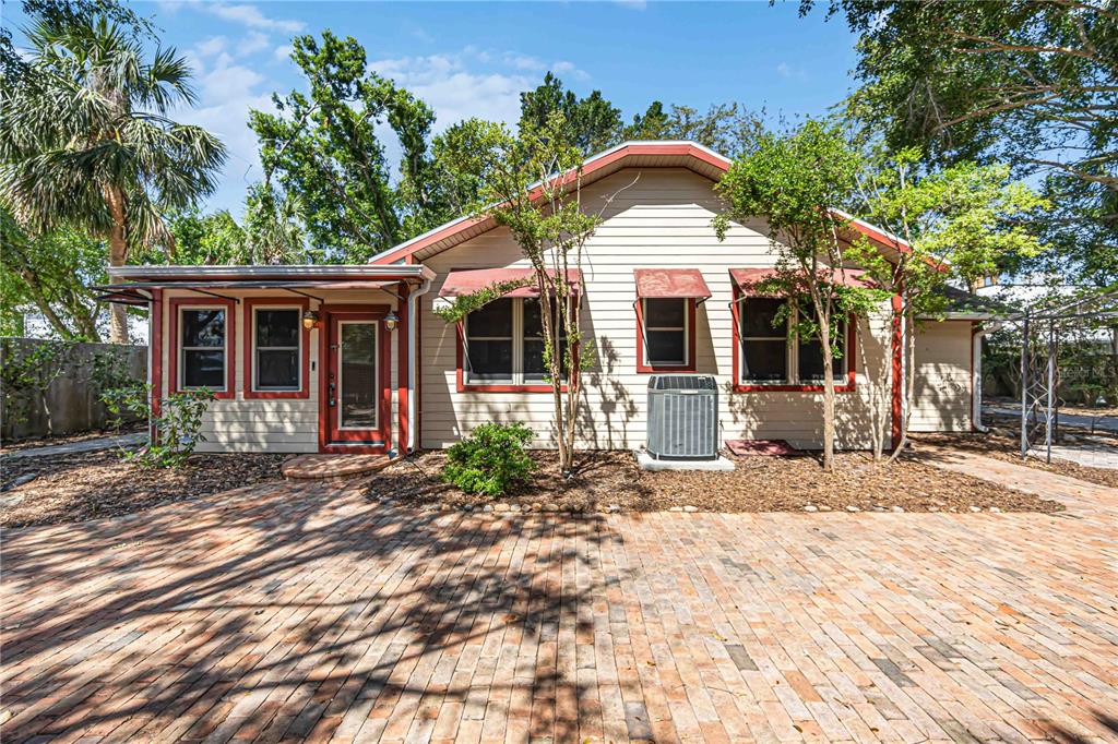 A brick patio leads to a single-story house with tan siding and red trim — 1743 8TH STREET, SARASOTA, FL