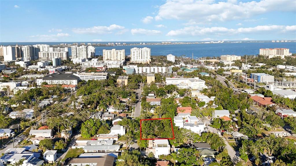 An aerial view shows a vacant, tree-covered lot outlined in red within a residential neighborhood — 1743 8TH STREET, SARASOTA, FL