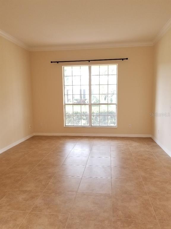 An empty room features beige walls, a large window with a curtain rod, and tiled flooring — 13448 ZORI LANE, WINDERMERE, FL