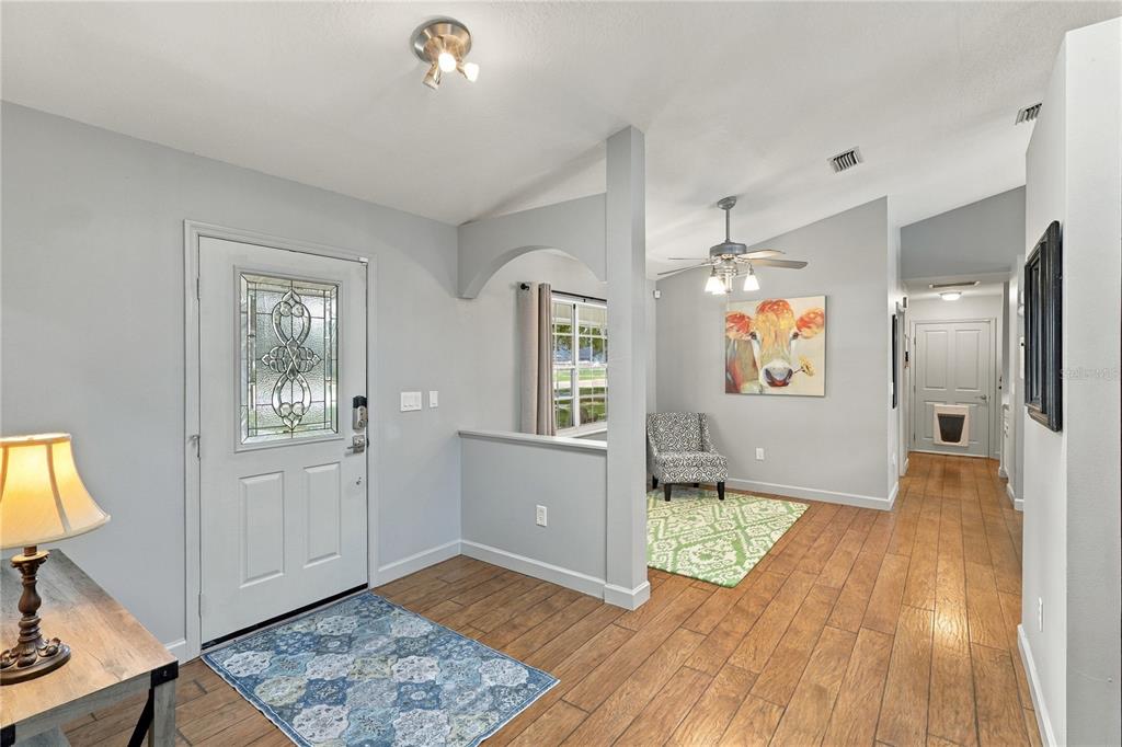 An entryway with light gray walls, wood-look flooring, a patterned rug, and a cow painting — 5718 NE 61ST AVENUE ROAD, SILVER SPRINGS, FL