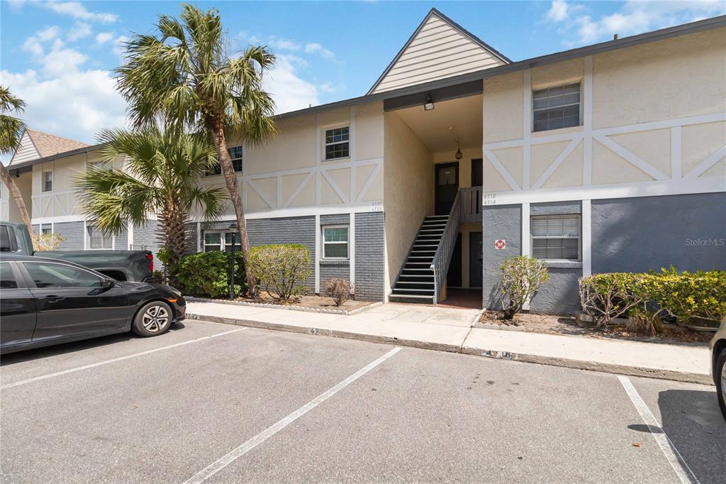A two-story apartment building exterior features a central staircase, gray brick, and tan siding — 4722 KILT COURT UNIT 65, ST CLOUD, FL