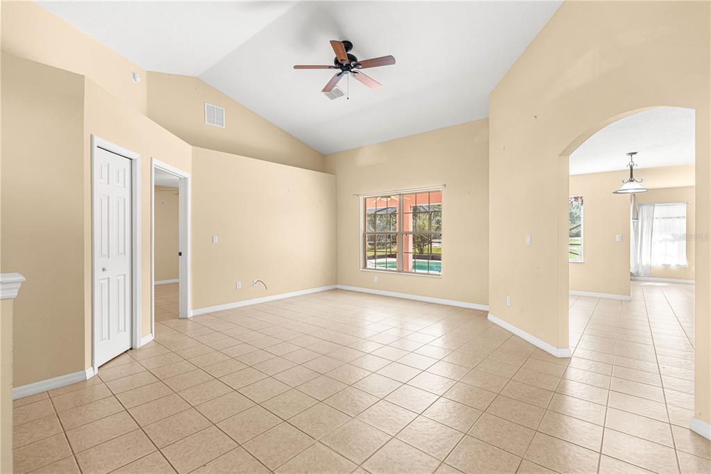 A spacious living room with vaulted ceilings, tile flooring, a ceiling fan, and arched doorways — 4731 SW GARDENIA COURT, DUNNELLON, FL