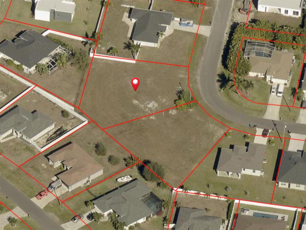 This aerial view shows a vacant residential lot outlined in red within a suburban neighborhood — 12 SW 25TH PLACE, CAPE CORAL, FL