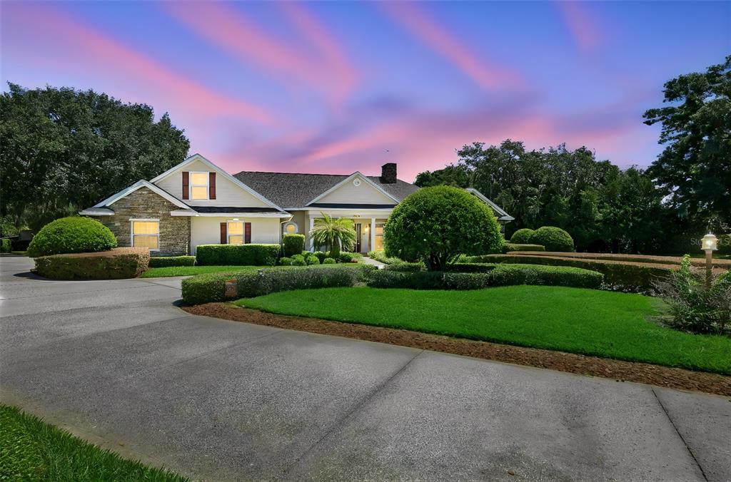 A single-story house with a stone facade and a large lawn under a sunset sky — 605 OLD MOUNT DORA ROAD, EUSTIS, FL