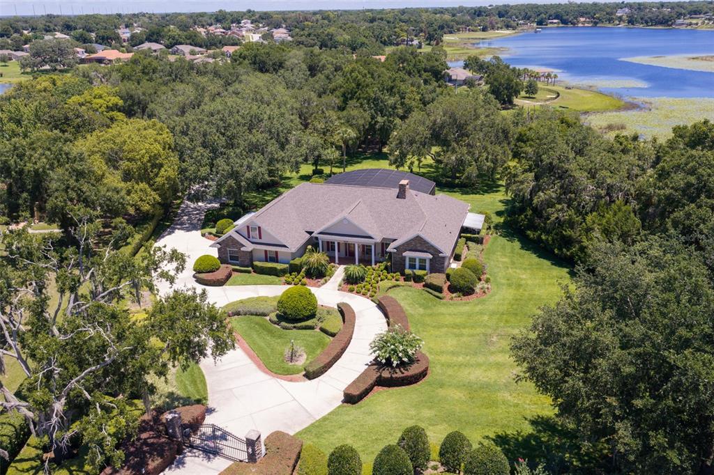 A covered brick porch features white columns, two wooden rocking chairs, and a landscaped yard — 605 OLD MOUNT DORA ROAD, EUSTIS, FL