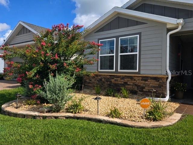 The exterior of a house features a stone facade, gray siding, and a landscaped garden — 5662 NW 40TH LOOP, OCALA, FL