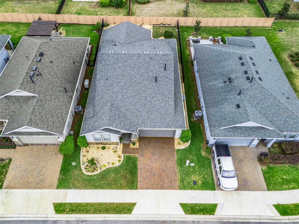 An aerial view shows three suburban houses with gray shingled roofs and paved driveways — 5662 NW 40TH LOOP, OCALA, FL