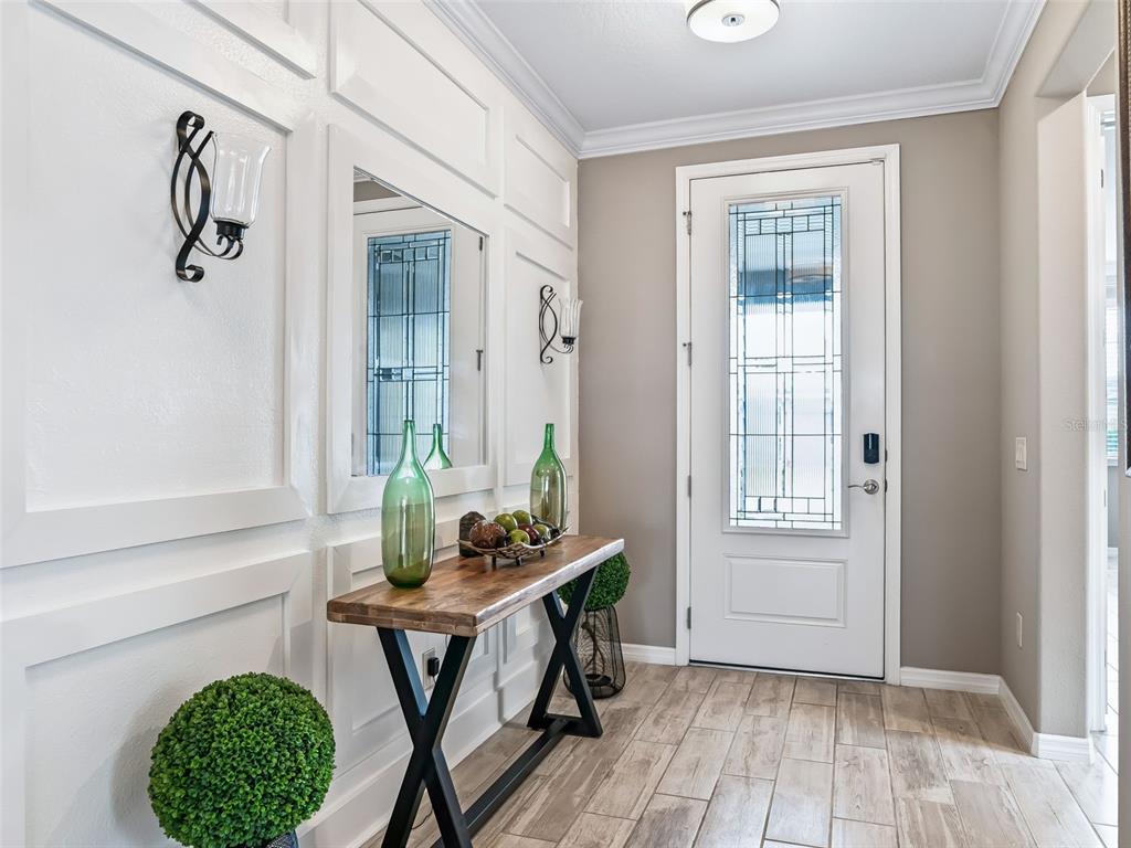 A foyer features a wooden console table, wall molding, a mirror, and a glass-paneled door — 5662 NW 40TH LOOP, OCALA, FL