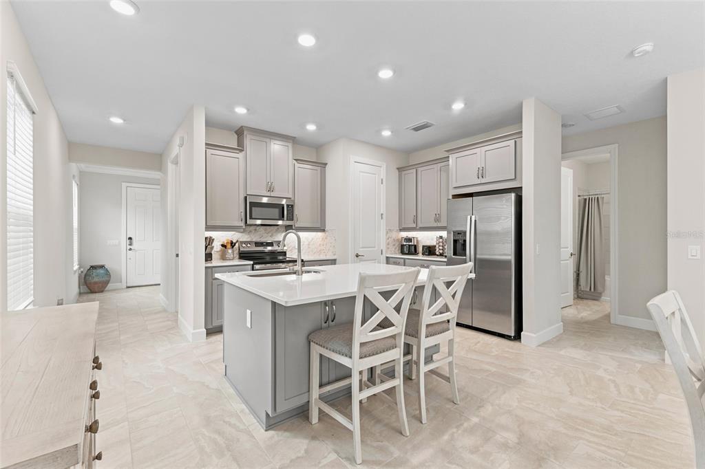 A kitchen with gray cabinets, a white island, stainless steel appliances, and light tile flooring — 1389 LAMBARDI COURT, POINCIANA, FL