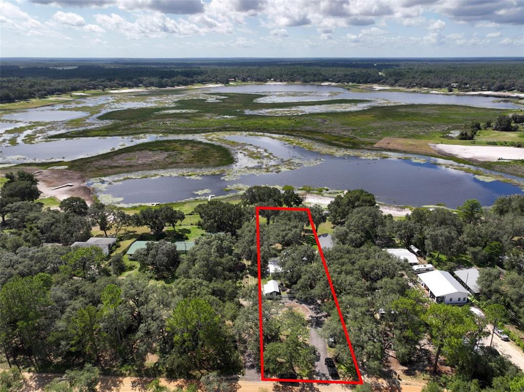 An aerial view shows a house on a wooded lot bordering a large lake — 5927 WHITE SANDS ROAD, KEYSTONE HEIGHTS, FL